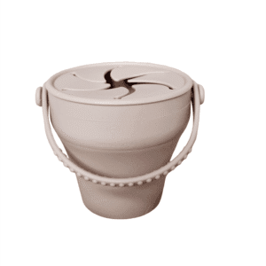 Taza de silicona plegable con tapa para snacks en color arena, ideal para niños pequeños.