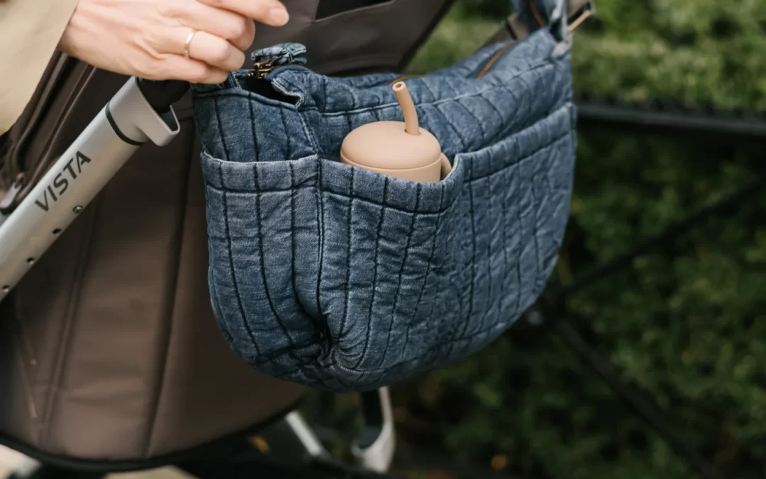 Bolsa del carrito del bebé abierta con pañales, toallitas y ropa organizada.